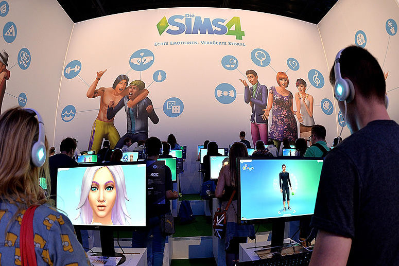 Visitors try out the game 'SIMS 4' at the Electronic Arts stand at the 2014 Gamescom gaming trade fair (Photo by Sascha Steinbach/Getty Images)